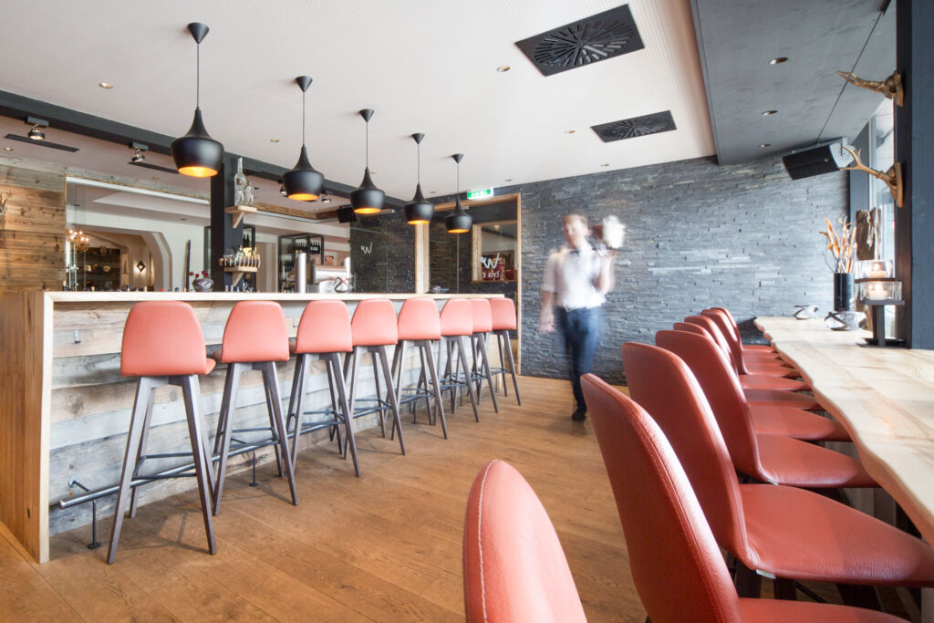 Moderne Bar mit roten Hockern und Bedienung in Bewegung.