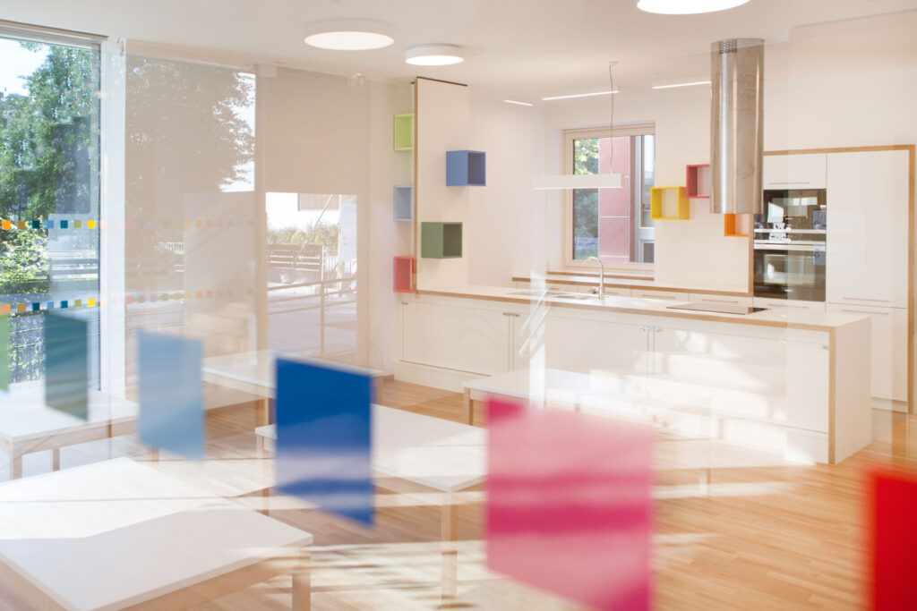 Heller Raum mit farbigen, würfelförmigen Dekoelementen an Wand und Glas.