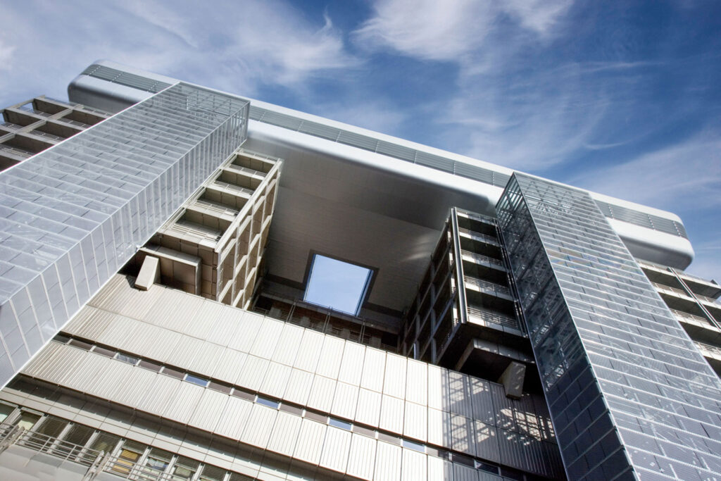 Blick nach oben auf moderne Gebäudearchitektur mit symmetrischem Durchbruch.