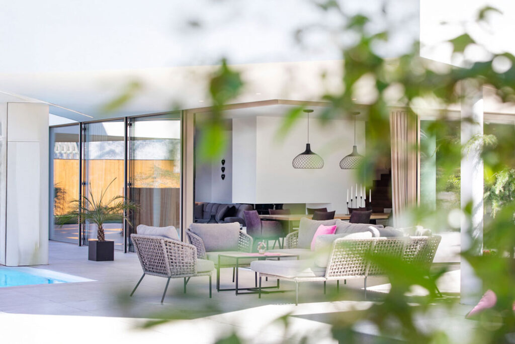 Blick auf eine moderne Terrasse mit Loungemöbeln und offenen Übergängen zum Innenraum.