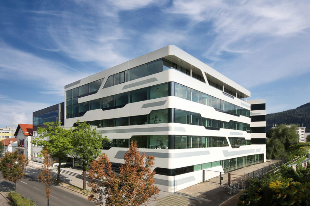 Moderne weiße Büroarchitektur mit horizontalen Fensterbändern und dynamischem Fassadendesign.
