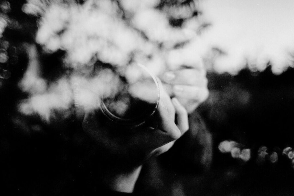 Hand mit Kamera in Schwarz-Weiß, Spiegelung