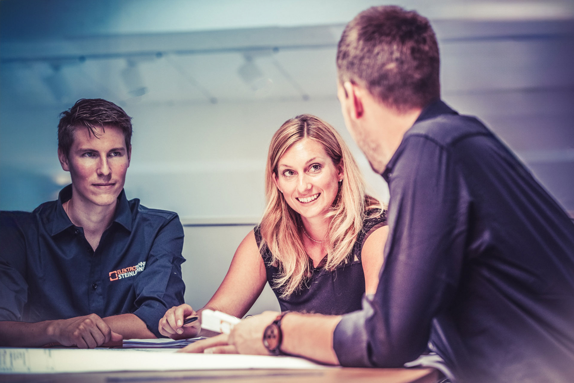 Frau im Gespräch mit Kollegen bei einem Meeting.