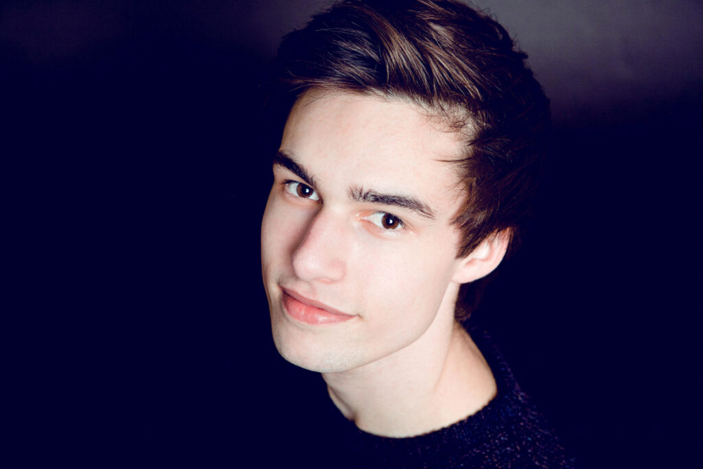 Junger Mann mit dunklem Haar blickt in die Kamera.