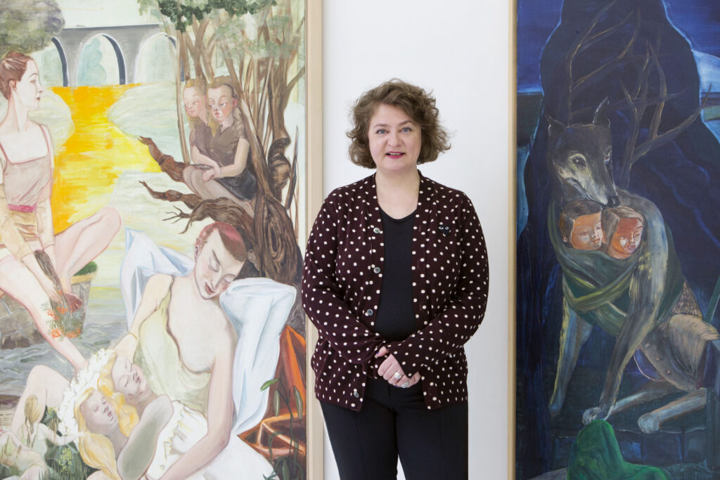 Frau steht zwischen zwei großformatigen Gemälden.